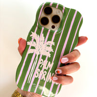 Green phone case with pink stripes and palm tree design held by a hand.